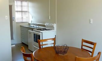 a kitchen with a stove and oven , wooden chairs around a table , and a vase in the center at Colonial Inn Motel