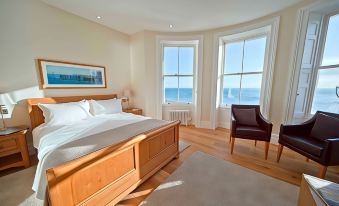 a large bedroom with a king - sized bed , hardwood floors , and a view of the ocean through three windows at A Room with A View