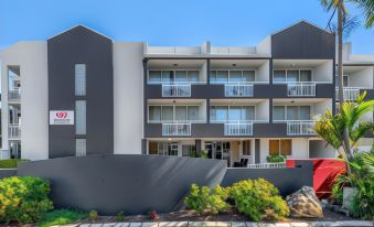 a modern building with a gray facade and balconies , surrounded by greenery and clear skies at The Wellington Apartment Hotel