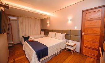 a large bed with a blue blanket is in the middle of a room with wooden floors and walls at Pousada Simpatia da Ilha