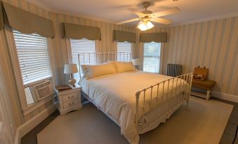 a large bedroom with a white bed in the center , surrounded by various pieces of furniture such as a couch , chairs , and a television at Inn at Tyler Hill