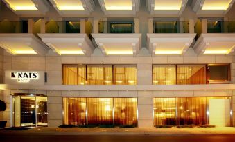a modern building with large glass windows and a reflective surface is illuminated by warm lights at Nafs Hotel