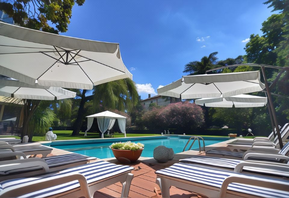 a large outdoor pool surrounded by lounge chairs and umbrellas , creating a relaxing atmosphere for guests at Blue Dream Hotel