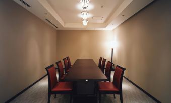 a long wooden table with red chairs is surrounded by beige walls in a room at Centrair Hotel