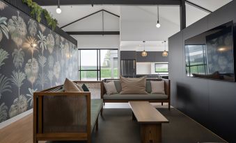 a modern living room with a wooden coffee table and a large screen on the wall at The Chamberson