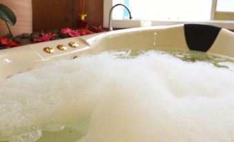 a bathtub filled with water and bubbles , with a view of a flower garden in the background at Lakeside Cottage Luxury B&B