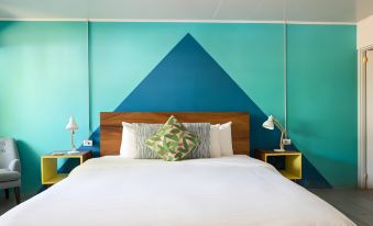 a bed with a white comforter and pillows is in a room with blue and green walls at Selina Jaco