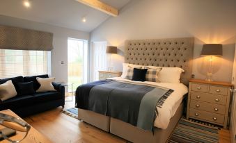 a spacious bedroom with a king - sized bed , hardwood floors , and a large window allowing natural light to fill the room at The White Horse Inn
