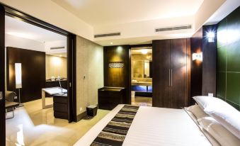 a modern hotel room with a large bed , wooden doors , and a bathroom in the background at Crown Victoria Hotel Tulungagung