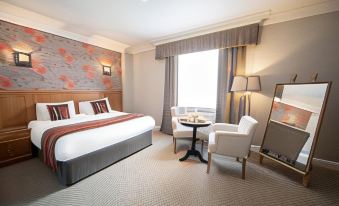 a modern hotel room with a bed , desk , and chair , as well as a small table and lamp at Whittlebury Hall and Spa