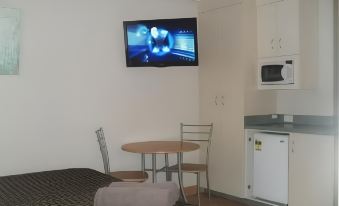 a hotel room with a bed , table , and chair , along with a tv mounted on the wall at Bali Hi Motel