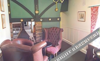 a room with a green wall , two brown armchairs , and a chandelier hanging from the ceiling at The Exeter Inn