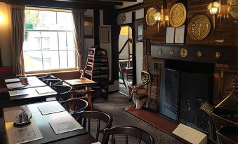 a room with a fireplace , wooden chairs , and tables is decorated with gold signs and other decorations at Sorrel Horse Inn