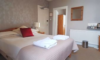 a neatly made bed with white towels and a red pillow in a hotel room at The George Hotel