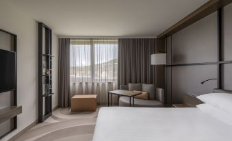 a modern hotel room with a large bed , couch , and window view , all decorated in neutral colors at Stuttgart Marriott Hotel Sindelfingen