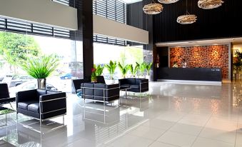 a modern hotel lobby with black chairs and white tiled floors , creating a comfortable and inviting atmosphere at Pinetree Hotel
