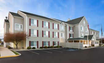 a modern hotel building with red and white shutters , surrounded by cars parked in the lot at Country Inn & Suites by Radisson, Toledo, Oh