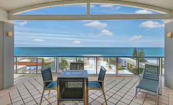 a modern , open - air terrace with a dining table and chairs overlooking the ocean , providing a panoramic view of the sea at Kings Row Apartments