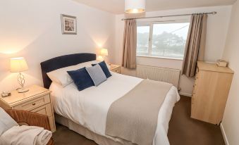 a cozy bedroom with a bed , nightstands , and a window , decorated in white and beige colors at Avondale