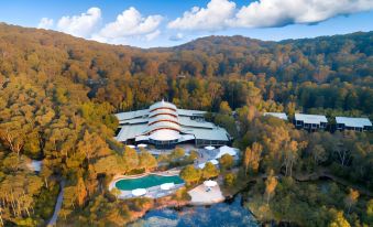 a large , modern building surrounded by trees and mountains , with a pool in the foreground at Kingfisher Bay Resort
