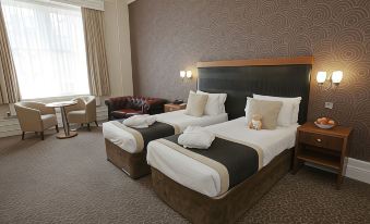 a hotel room with two beds , one on the left side and another on the right side of the room at Midland Hotel, Bradford