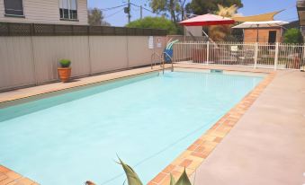 a backyard with a swimming pool surrounded by chairs and umbrellas , creating a relaxing atmosphere at Waterview Motel Maclean