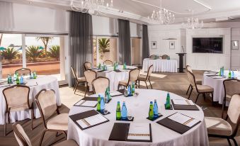 a conference room set up for a meeting , with multiple tables and chairs arranged in a semicircle at Beverly Hills