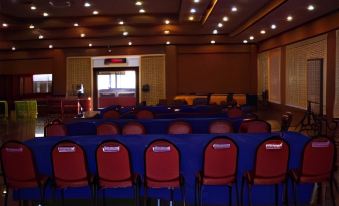 a large conference room with rows of red chairs arranged in a semicircle around a long table at Lopburi Residence Hotel