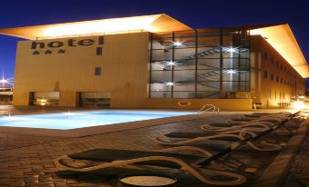 a hotel with a pool and lounge chairs in front of it at night at Posadas de Espana Malaga