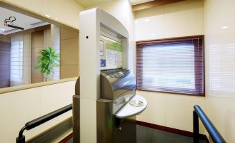 a modern office setting with a white atm machine , a window , and a potted plant at Daiwa Roynet Hotel Hachinohe