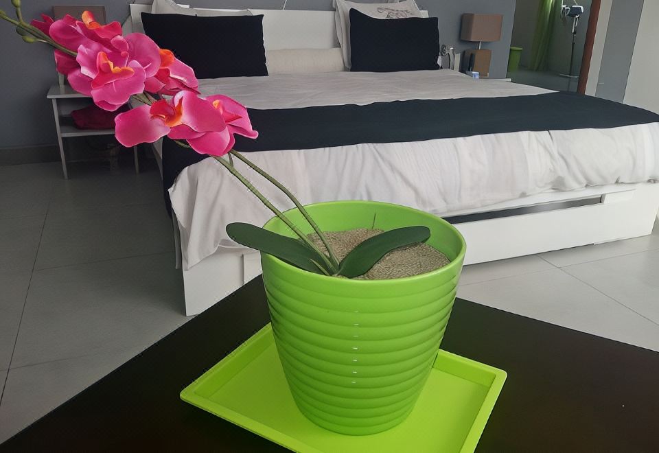 a green cup with a plant in it is sitting on a table next to a bed at The Sanctuary