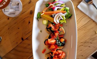 a dining table with a white plate containing a salad and a glass of beer at The Punch Bowl