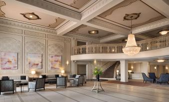 a grand hotel lobby with elegant chandeliers , marble floors , and various seating areas for guests at Hilton St. Louis Frontenac