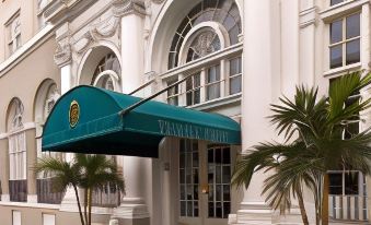"a building with a green awning and several potted plants , one of which has a sign that says "" stannum ""." at The Terrace Hotel Lakeland, Tapestry Collection by Hilton