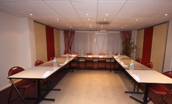 a conference room set up for a meeting , with several chairs arranged in a semicircle around a table at Ibis Clermont-Ferrand Sud Carrefour Herbet