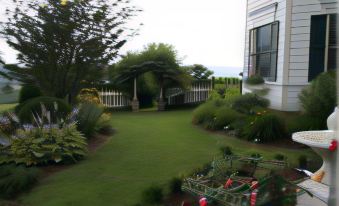 a beautiful backyard with lush green grass , a wooden fence , and various plants and flowers at Harmony Hill Bed & Breakfast