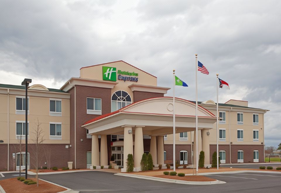 the exterior of a holiday inn express hotel with multiple flags flying in front of the entrance at Holiday Inn Express Pembroke