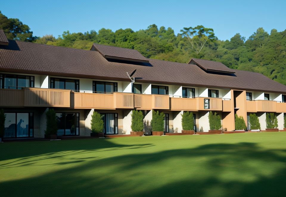 a large house with a brown roof and balconies is surrounded by a green lawn at DoiTung Lodge