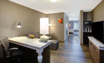 a modern hotel room with wooden flooring , white furniture , and a white desk with a lamp at Hilton Garden Inn Merrillville