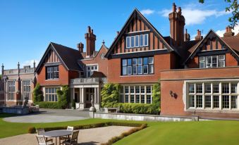 a large , red brick house with a green lawn in front of it , surrounded by trees at Macdonald Elmers Court Hotel