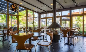 a dining room with a large round table surrounded by chairs , and a fireplace in the background at Clarion Collection Hotel Carlscrona