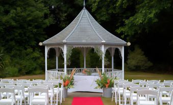 a wedding ceremony is taking place in a gazebo , with chairs set up for guests and flowers on a red carpet at Alton House Hotel