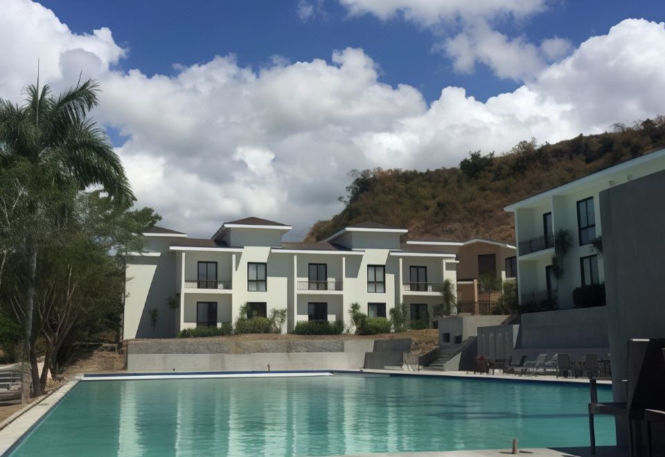 a large swimming pool is surrounded by a row of modern apartment buildings on a hillside at Thunderbird Resorts - Rizal