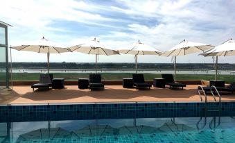 There is a swimming pool with chairs and umbrellas located next to other pools at Aaron Vientiane Hotel