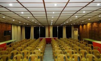 a large , empty conference room with rows of yellow chairs and a red cloth - covered stage at Bantayan Island Nature Park and Resort