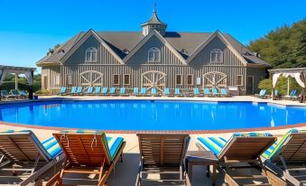 a large wooden building with a swimming pool in front of it , surrounded by lounge chairs at Barnsley Resort