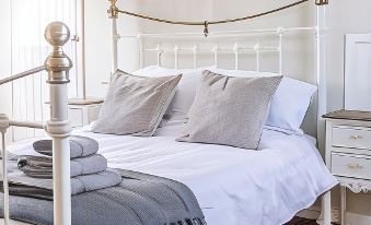 a white bedroom with a large bed , a wooden floor , and various pieces of furniture at The Golden Key