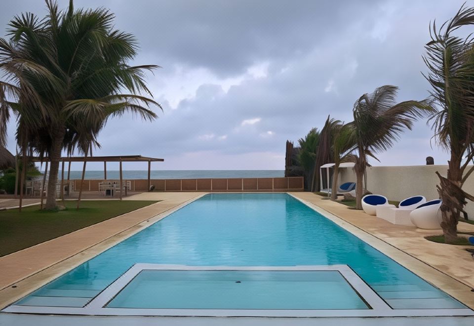 a large swimming pool with a long , rectangular shape is surrounded by palm trees and lounge chairs at Dolphin Beach Resort
