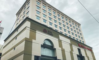 a tall building with a red sign on top and a logo in the corner at Classic Hotel Muar