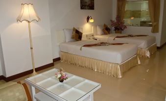 a hotel room with two beds , a coffee table , and a window , decorated with white walls and gold accents at Bay Hotel Srinakarin
